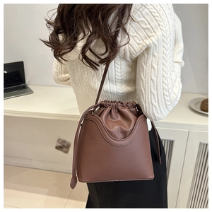 Brown vintage drawstring bucket bag with U-shaped stitching shown on a model's shoulder