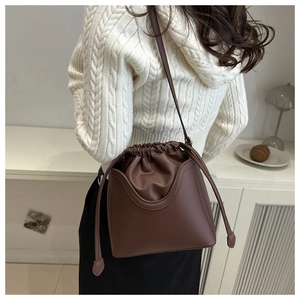 Detail of vintage brown drawstring bucket bag with unique dual-layer shell design on model