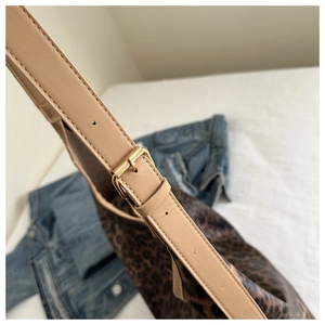 Détail d'une bandoulière en cuir beige réglable avec boucle dorée sur sac léopard