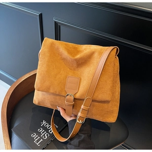 Close-up of vintage brown suede messenger bag with textured buckle and leather strap