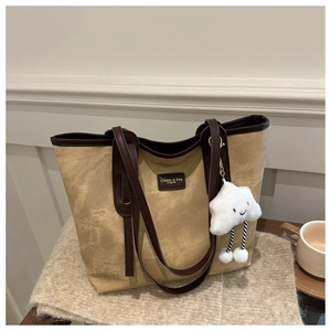 Detail of khaki tote bag with brown leather trim and cute white cloud plush pendant