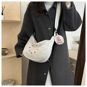 Détail du sac bandoulière en velours beige avec broderie rouge et petit porte-monnaie