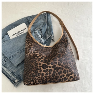 Gros plan d'un sac cabas léopard avec bandoulière en cuir brun et boucle en métal