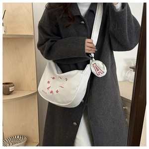 Detailed texture of white corduroy shoulder bag with red embroidery and small coin pouch