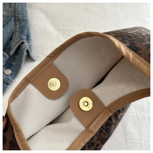 Détail des fermoirs magnétiques et motif léopard sur un grand sac à bandoulière