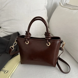 Sac seau rétro marron foncé avec poignée nouée et lettrage fashion dans un décor chic