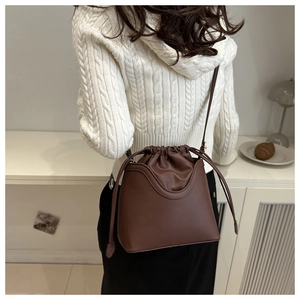 Detail view of a vintage dark brown leather bucket bag with elegant drawstring design