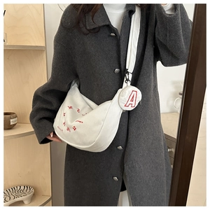 Close-up of white corduroy crescent bag with red embroidery and matching round coin purse