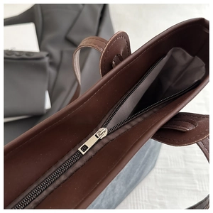 Top view detail of dark brown tote bag showing silver zipper and magnetic clasp closure