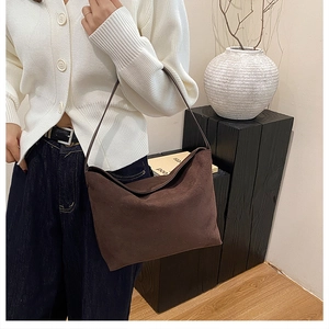 Texture détaillée du grand sac cabas en daim marron avec fines bandoulières en cuir