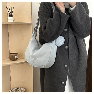 Detail of light blue corduroy crescent bag with white embroidery and round coin pouch