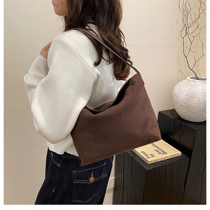 Détail du sac hobo en daim marron foncé avec texture douce et bandoulière porté par modèle