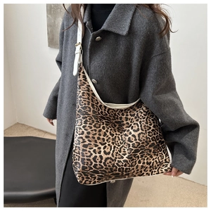 Détail d'un sac cabas léopard avec lanières en cuir blanc porté par le mannequin