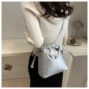 Detail of silver matte leather bucket bag featuring a drawstring closure and U-shaped stitching