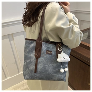 Detail of blue marble pattern tote bag with leather straps and cloud charm accessory