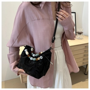 Detail of glossy pleated bucket bag with colorful beaded chain and thin shoulder strap