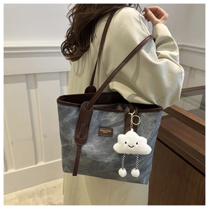 Detail of gray marble canvas tote bag with brown leather trim and cute cloud charm accessory
