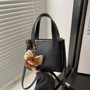 Borsa a secchiello minimalista in pelle nera con ciondolo in peluche e manici superiori