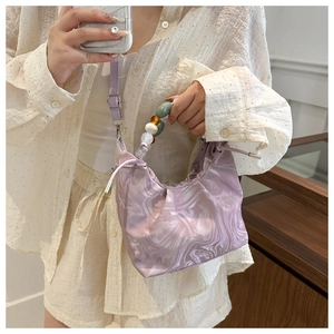 Detail of purple marble pattern hobo bag with colorful beaded handle and drawstring closure