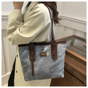 Detail of a large marble texture tote bag with leather straps on a model wearing a coat