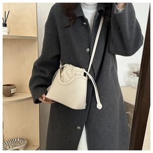 Detail of cream white bucket bag featuring soft drawstring closure and matte leather texture