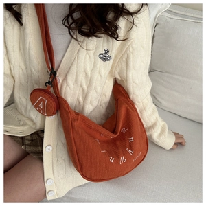 Détail du sac croissant en velours côtelé orange avec broderie et petite pochette ronde