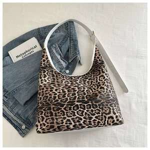 Gros plan du sac fourre-tout à imprimé léopard avec bandoulière blanche et accessoires
