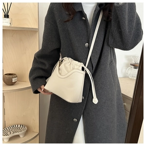 Detail of beige drawstring bucket bag with leather frame and fabric inner lining