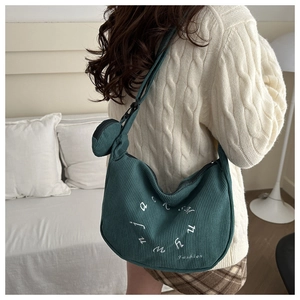 Détail du sac croissant en velours côtelé vert foncé avec mini pochette et broderie