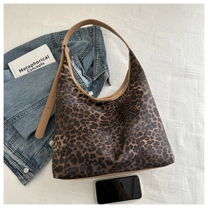 Détail d'un sac cabas léopard avec bandoulière réglable sur une veste en jean
