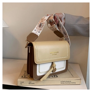 Detailed shot of tricolor crossbody bag with woven edges and floral fabric strap