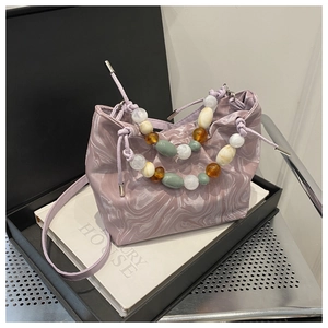 Detail of purple marble bucket bag with distinctive beaded handle and drawstring closure