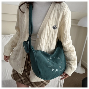 Détail d'un sac hobo en velours côtelé vert avec broderie et mini pochette ronde assortie