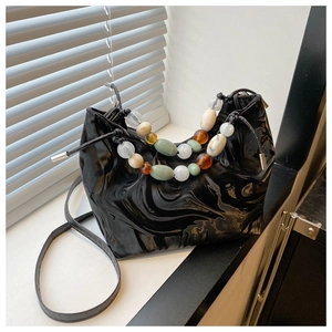 Detail of marble textured black handbag with colorful beaded handle on a window sill