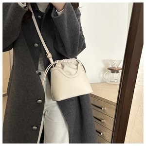 Detailed close-up of a minimalist cream bucket bag with drawstring closure and strap