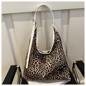 Détail du sac hobo léopard avec bandoulière en cuir blanc posé sur une chaise