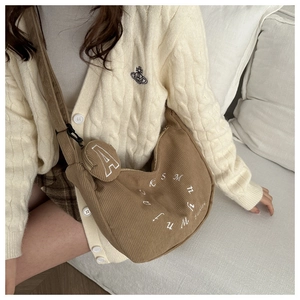 Detail of a brown corduroy tote bag with embroidered letters and a mini round pouch