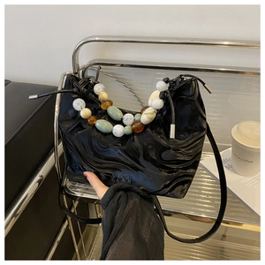 Detail of black marble pattern handbag featuring colorful beaded handle and soft pleats