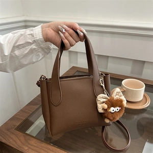 Fashionable brown litchi pattern leather bucket bag with a cute monster plush charm