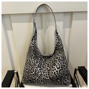 Détail d'un grand sac hobo à motif léopard posé sur une chaise dans un décor intérieur