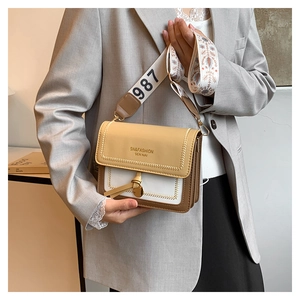 Detail of tricolor crossbody bag with wide floral embroidered strap and gold clasp