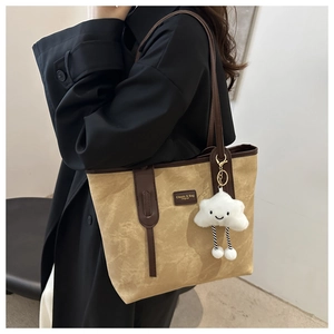Detail of khaki canvas tote with brown leather handles and a plush cloud charm