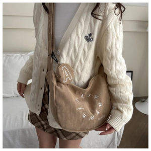 Detail of a brown corduroy half-moon crossbody bag with an embroidered round coin purse