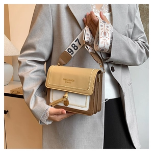 Detail of trendy color-block crossbody bag with floral jacquard strap and brand embossing