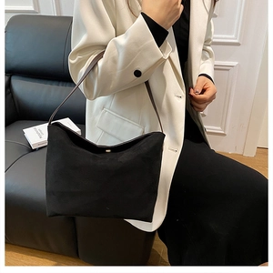 Détail du sac hobo en daim noir avec boucle dorée et bandoulière en cuir marron foncé