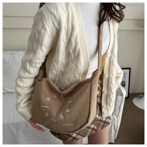 Detail of khaki corduroy tote bag with fashion embroidery on casual knit sweater