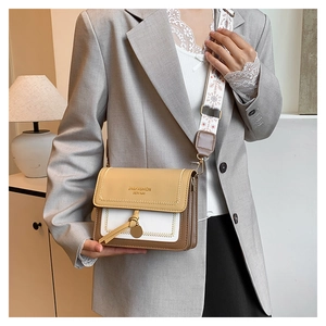 Detail of color-block flap bag with jacquard strap worn by a model in grey suit