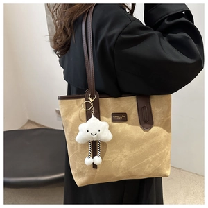 Detail of canvas tote bag with brown leather handles and plush cloud charm accessory