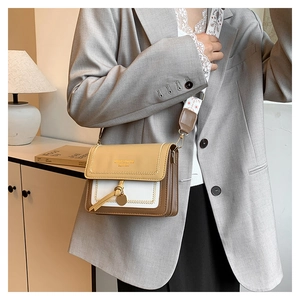 Detail of color-block flap bag with leather tassel and floral embroidered shoulder strap