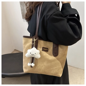 Detail of khaki canvas tote bag featuring brown leather trim and a cute cloud charm